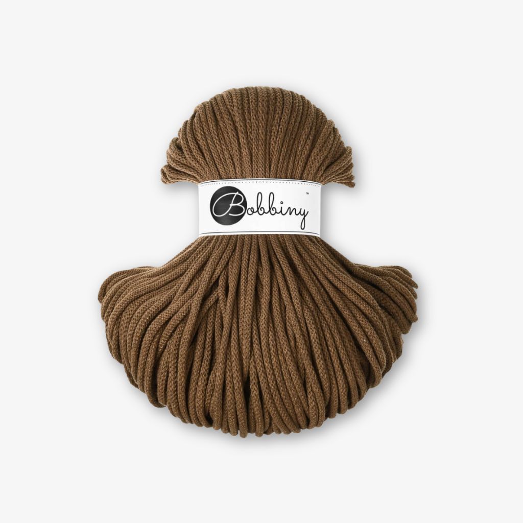 Terracotta Bobbiny Kordel mit Banderole vor grauem Hintergrund.